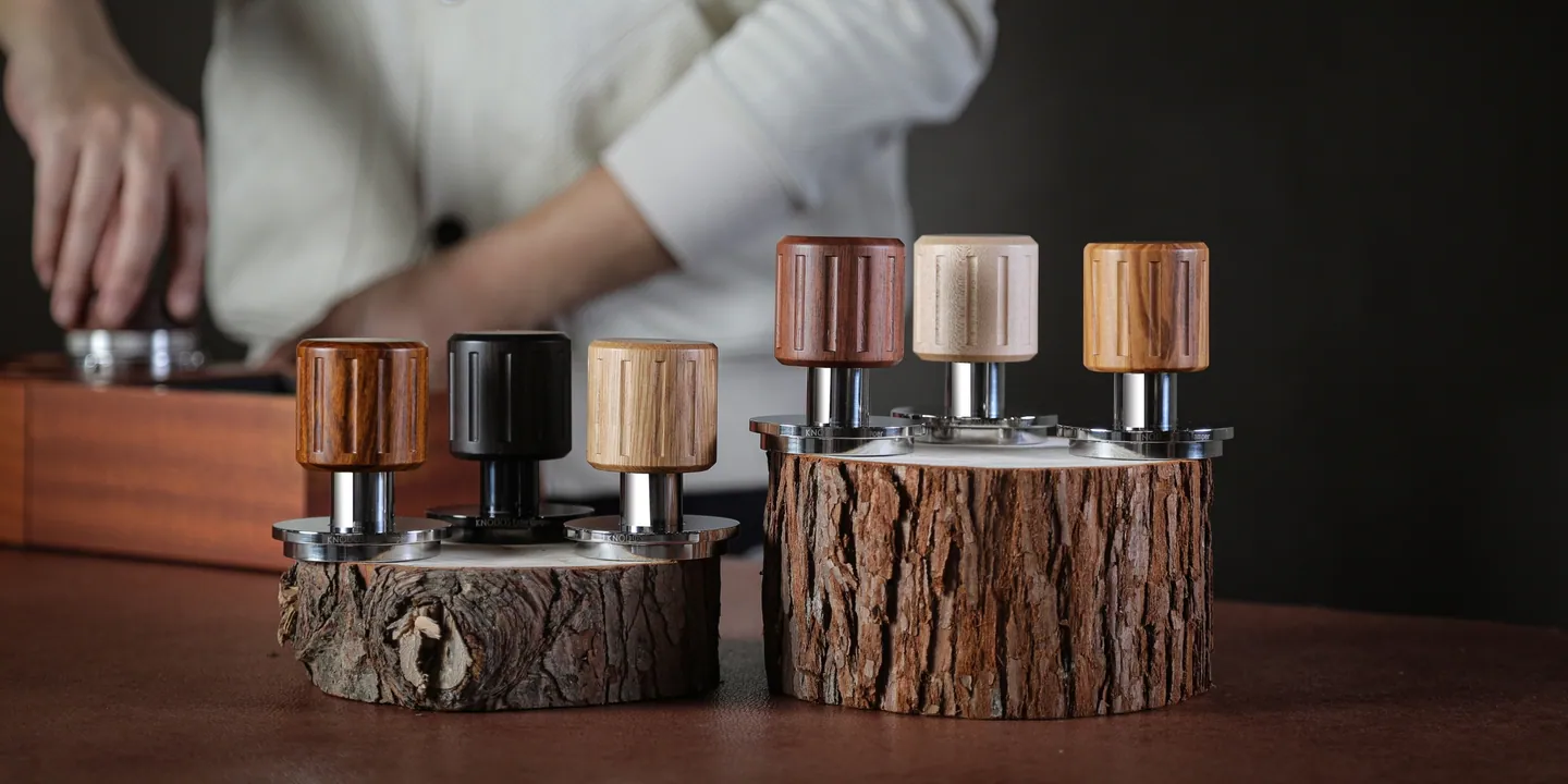 Six calibrated tampers in different woods on a bark stand