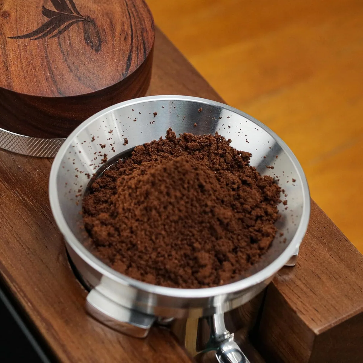 A bottomless portafilter of ground coffee resting on a wooden board