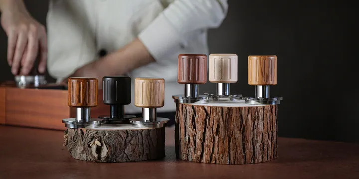 Six calibrated tampers in walnut, maple and olive wood on a bark stand